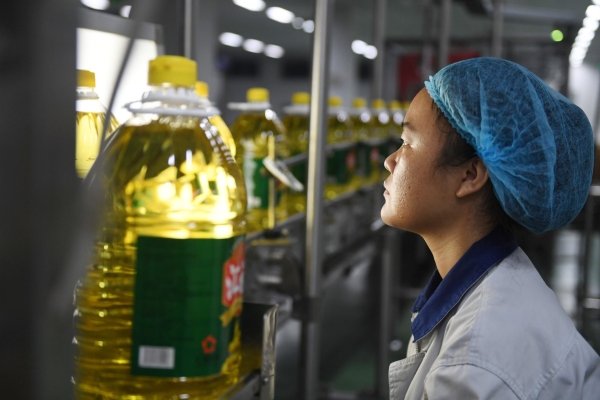 A Chinese worker examines a bottle of soybean oil