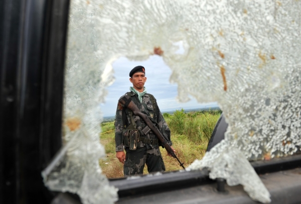 PHILIPPINES, NOVEMBER 25 - A military trooper is framed by a hole of a car window, one of the vehicles found at the crime scene where gunmen massacred dozens of people in Maguindanao province. Philippine President Gloria Arroyo vowed to hunt down the perpetrators as one of her political allies was named the prime suspect. (Ted Aljibe/AFP/Getty Images)