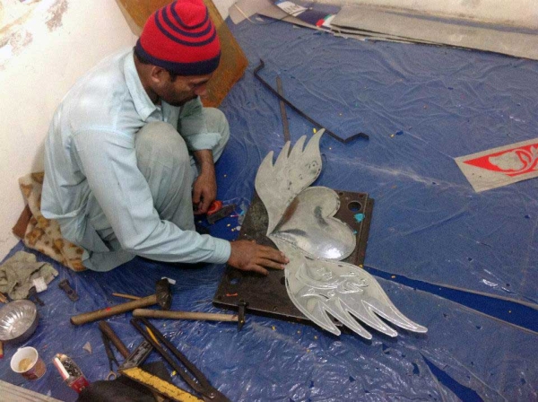 A rickshaw artist hammers out a design on a metal ornament. (Pakistan Youth Alliance)