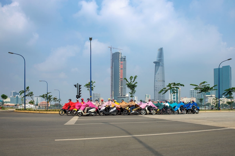 A still from a video set in Ho Chi Minh City that follows twenty-eight scooter riders literally connected by their brightly colored ponchos and identical face masks.