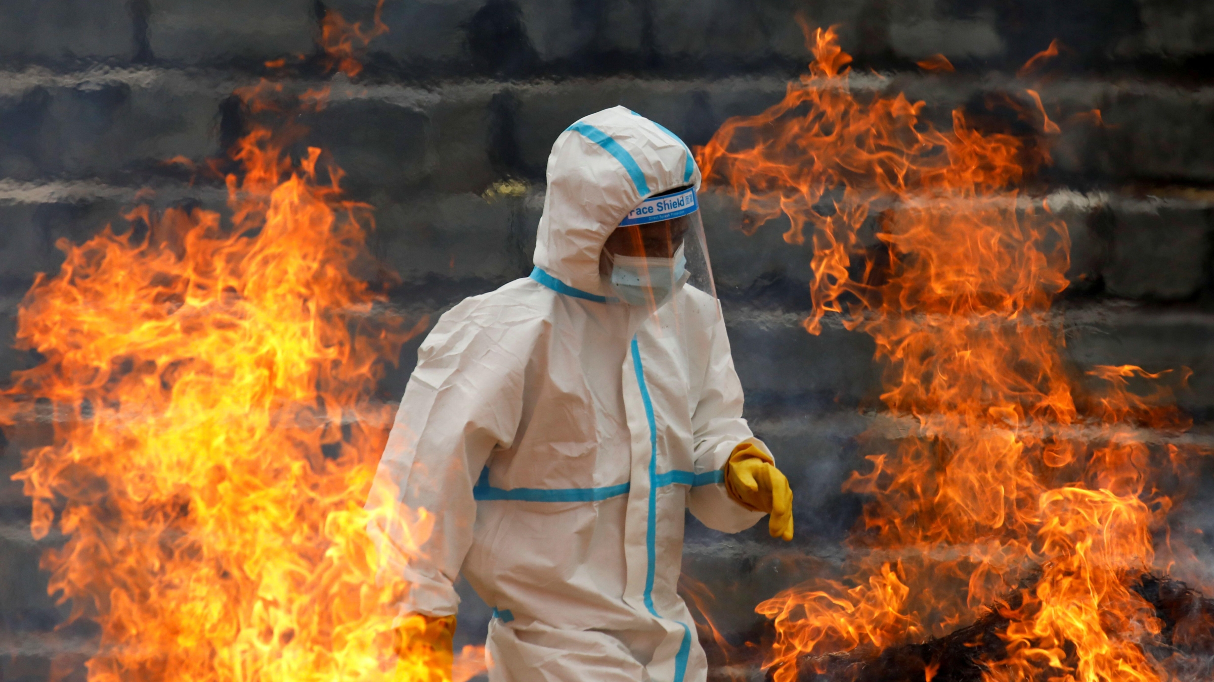 A man wearing personal protective equipment helps cremate the bodies of COVID-19 victims.