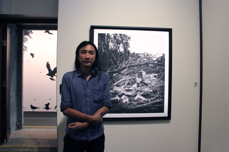 Participating artist South Ho standing next to a work from his Whiteness of Trees (2018) photograph series.